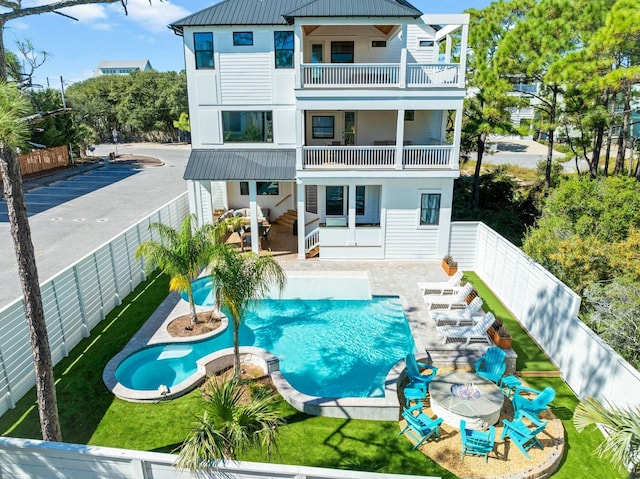 back of property featuring a balcony, a patio, and a fenced in pool