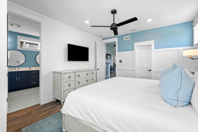 bedroom with dark wood-type flooring, ceiling fan, ensuite bathroom, and sink