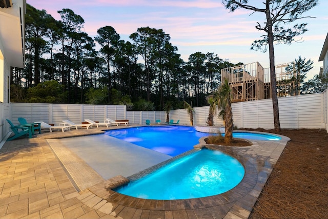 pool at dusk featuring a patio