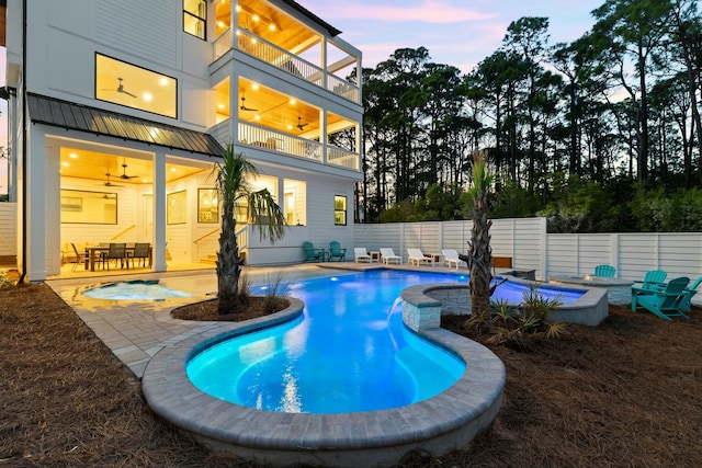 pool at dusk with a hot tub, ceiling fan, and a patio area