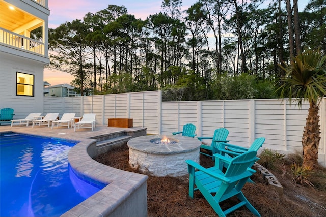 pool at dusk featuring a patio area and an outdoor fire pit