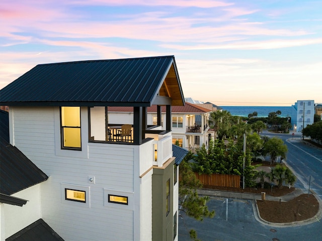 property exterior at dusk with a balcony and a water view