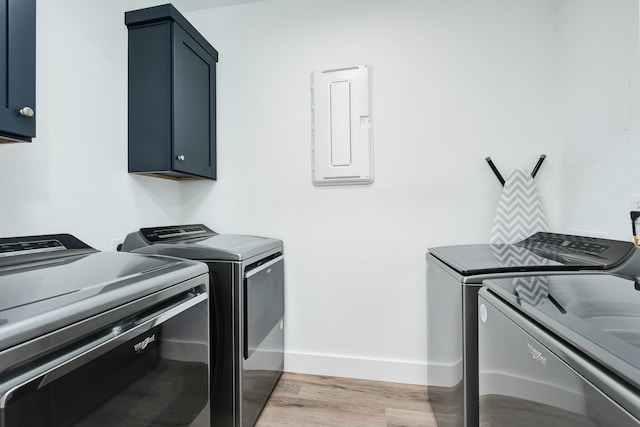 washroom featuring cabinets, electric panel, washer and clothes dryer, and light hardwood / wood-style floors