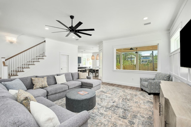 living room featuring hardwood / wood-style flooring, ceiling fan, and crown molding