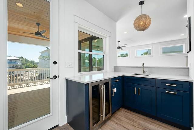 bar featuring blue cabinets, sink, beverage cooler, ceiling fan, and light wood-type flooring