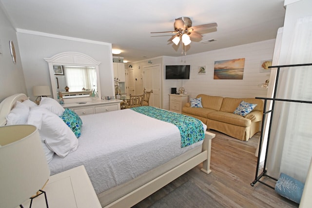 bedroom with hardwood / wood-style flooring, ceiling fan, and crown molding