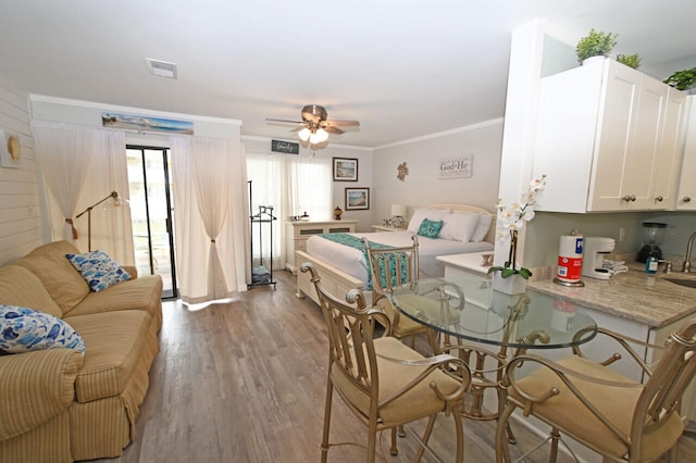 dining area with ceiling fan, sink, crown molding, and light hardwood / wood-style flooring