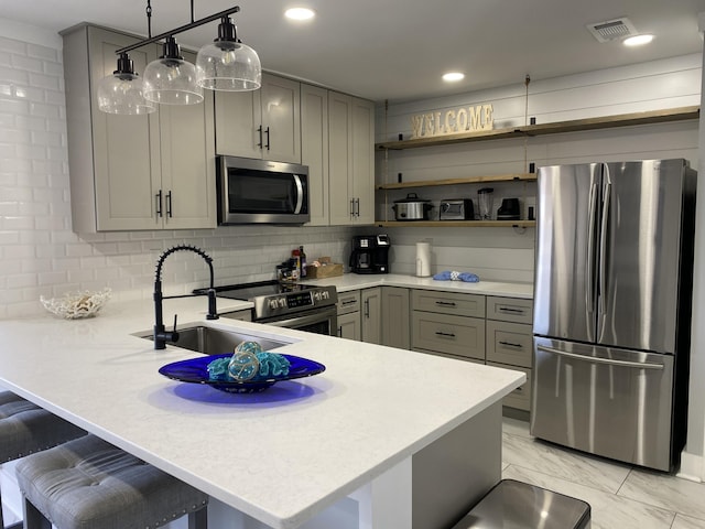 kitchen with kitchen peninsula, appliances with stainless steel finishes, a breakfast bar, and decorative light fixtures