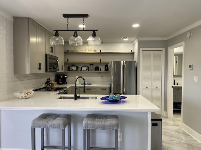 kitchen with kitchen peninsula, appliances with stainless steel finishes, sink, gray cabinets, and a breakfast bar area