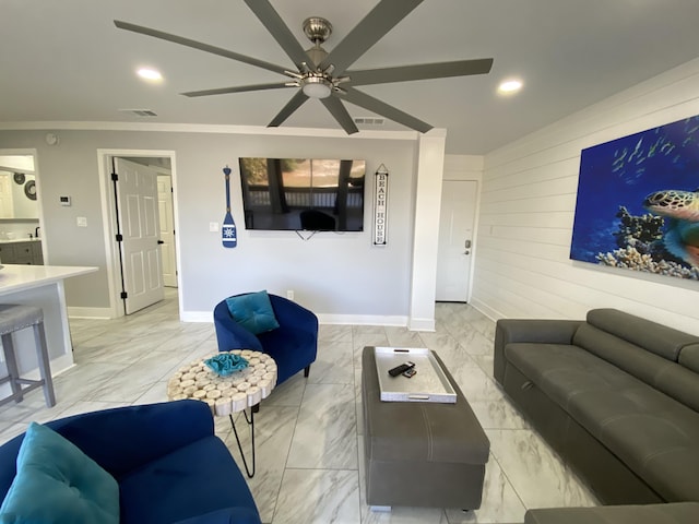 living room featuring crown molding, ceiling fan, and wooden walls