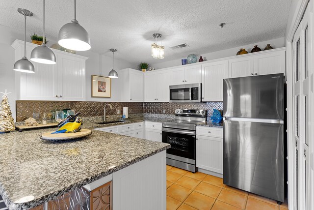 144 Spires Ln Unit 114, Santa Rosa Beach, FL 32459 - kitchen with pendant lighting, sink, white cabinets, kitchen peninsula, and stainless steel appliances