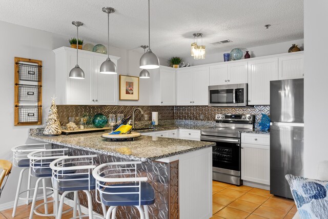 144 Spires Ln Unit 114, Santa Rosa Beach, FL 32459 - kitchen featuring a breakfast bar, sink, decorative light fixtures, appliances with stainless steel finishes, and kitchen peninsula