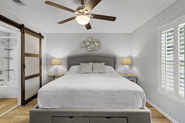 144 Spires Ln Unit 114, Santa Rosa Beach, FL 32459 - bedroom with ceiling fan, a barn door, light hardwood / wood-style floors, and a textured ceiling
