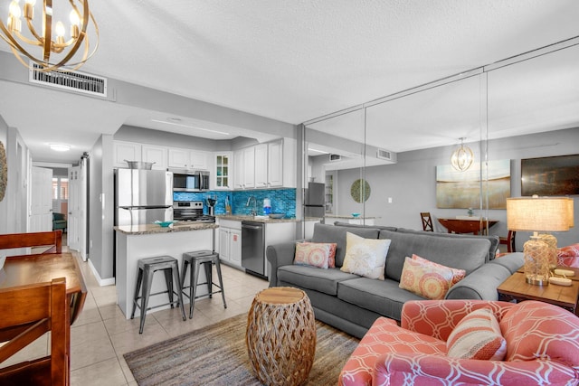 living room with sink, a textured ceiling, a chandelier, and light tile patterned floors