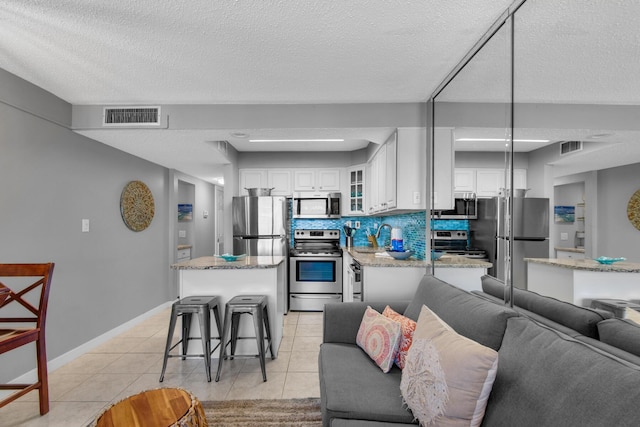 living room featuring sink, light tile patterned flooring, and a textured ceiling