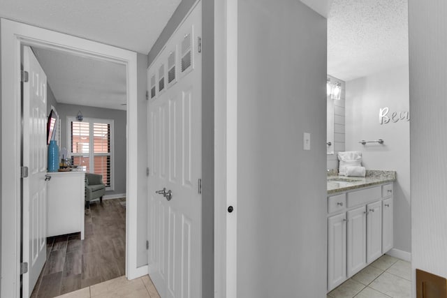 hallway featuring a textured ceiling, light tile patterned floors, and sink