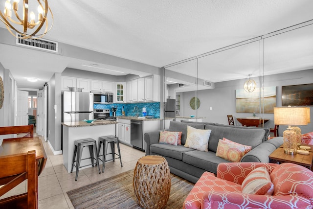 tiled living room with sink, a textured ceiling, and a chandelier