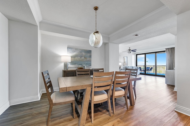 dining space featuring ceiling fan, crown molding, wood-type flooring, and a textured ceiling