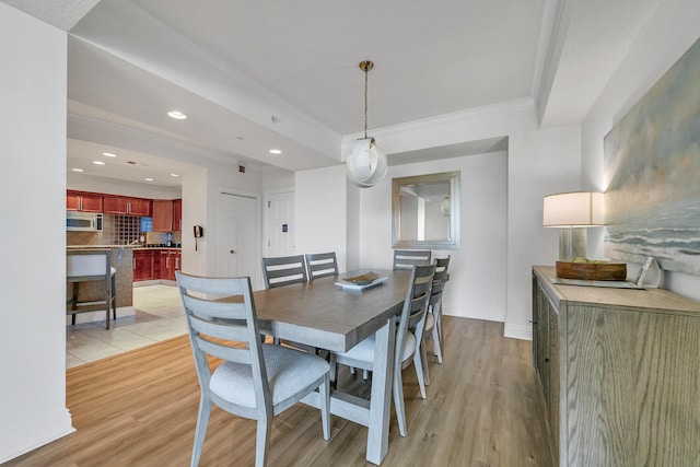 dining area with light wood-type flooring and ornamental molding