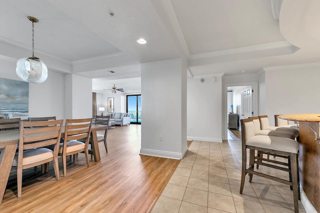 dining space featuring a tray ceiling, ceiling fan, light hardwood / wood-style floors, and ornamental molding