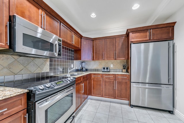 kitchen featuring light stone countertops, appliances with stainless steel finishes, backsplash, crown molding, and light tile patterned flooring