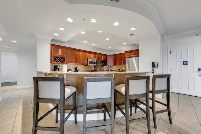 kitchen with kitchen peninsula, light tile patterned flooring, stainless steel appliances, and ornamental molding