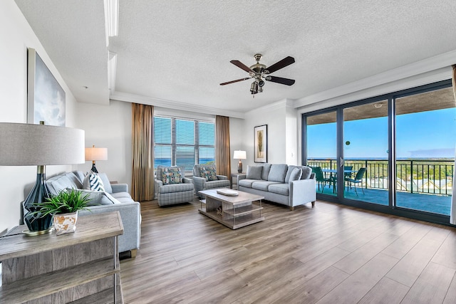 living room featuring a textured ceiling, hardwood / wood-style flooring, ceiling fan, and ornamental molding