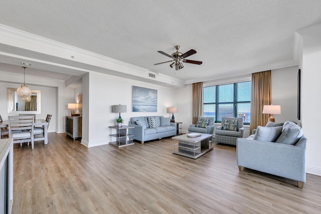 living room with ceiling fan, crown molding, a textured ceiling, and light wood-type flooring