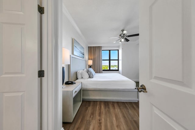 bedroom featuring a textured ceiling, ceiling fan, ornamental molding, and dark wood-type flooring