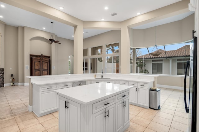 kitchen with ceiling fan, sink, a kitchen island, fridge, and white cabinets