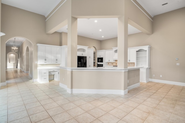 kitchen with white cabinetry, a towering ceiling, a spacious island, light tile patterned floors, and black appliances