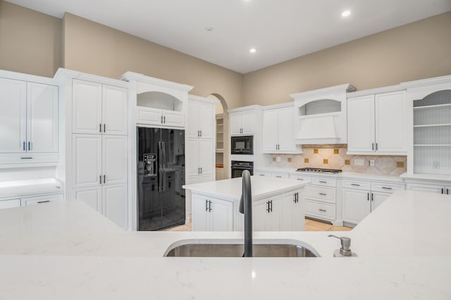 kitchen with tasteful backsplash, white cabinetry, and black appliances