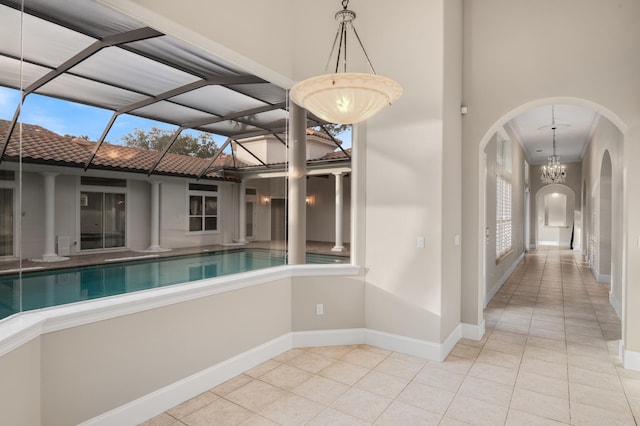 hall with an inviting chandelier, plenty of natural light, and light tile patterned flooring