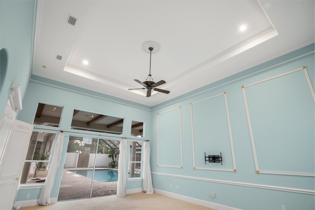 interior space with carpet floors, a tray ceiling, and ceiling fan