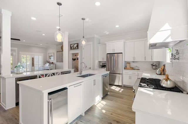 kitchen featuring sink, premium range hood, an island with sink, white cabinets, and appliances with stainless steel finishes