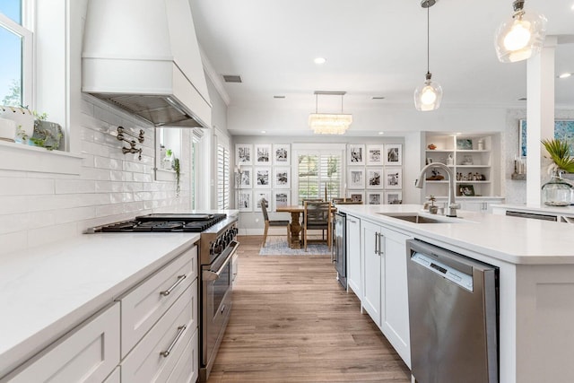 kitchen featuring sink, stainless steel appliances, pendant lighting, white cabinets, and custom exhaust hood