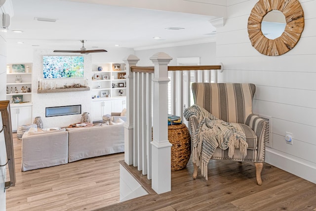 sitting room with plenty of natural light, crown molding, and light hardwood / wood-style flooring