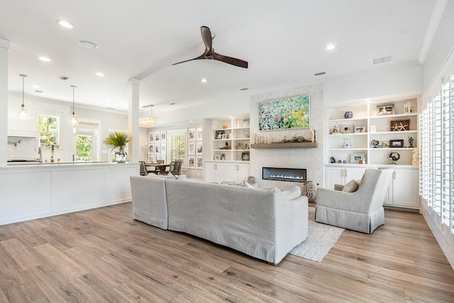 living room with crown molding, light hardwood / wood-style flooring, and ceiling fan