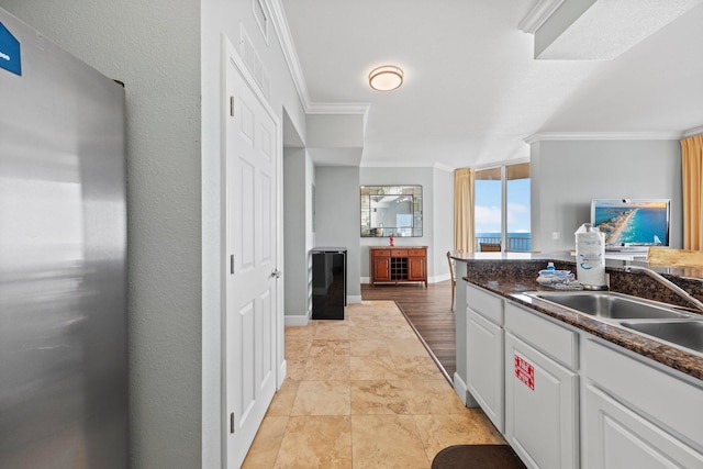 kitchen featuring white cabinets, sink, dark stone countertops, ornamental molding, and a wall of windows