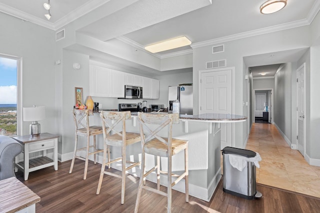 kitchen with kitchen peninsula, appliances with stainless steel finishes, white cabinetry, and a kitchen breakfast bar