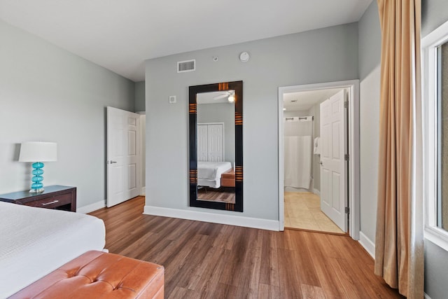 bedroom with hardwood / wood-style flooring and connected bathroom