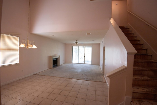 unfurnished living room with light carpet, a high ceiling, and ceiling fan with notable chandelier