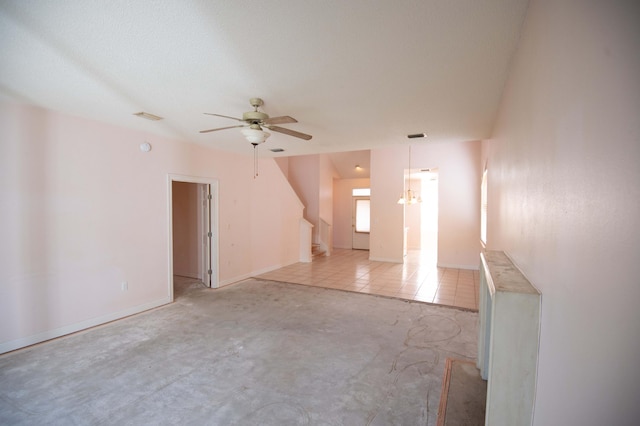 unfurnished living room with a textured ceiling, ceiling fan with notable chandelier, and light tile patterned flooring