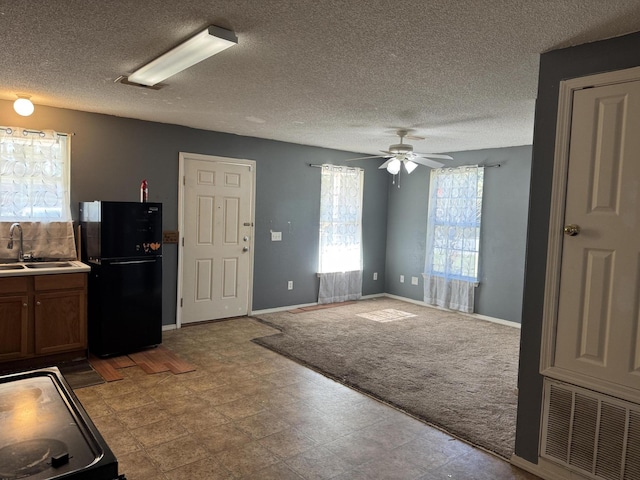 kitchen with black refrigerator, light carpet, a textured ceiling, ceiling fan, and sink