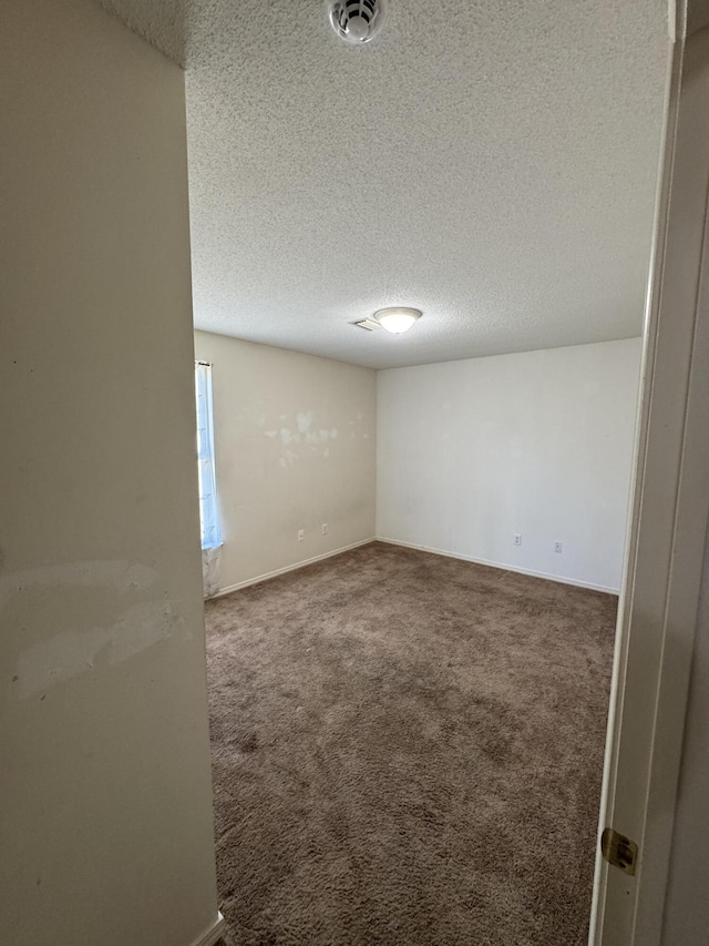 unfurnished room with dark carpet and a textured ceiling