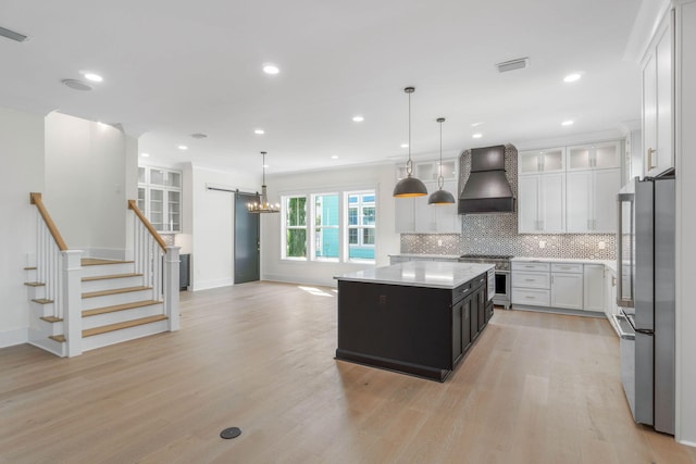 kitchen featuring decorative backsplash, custom range hood, a kitchen island, decorative light fixtures, and white cabinetry