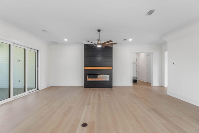 unfurnished living room with a healthy amount of sunlight, a large fireplace, ceiling fan, and ornamental molding