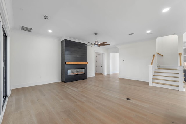 unfurnished living room with ceiling fan, light wood-type flooring, a fireplace, and ornamental molding