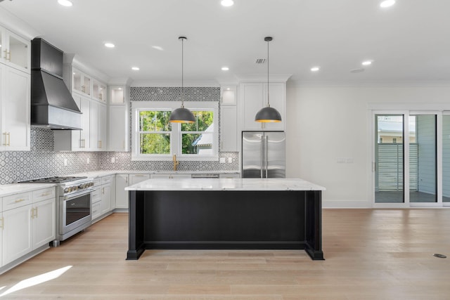 kitchen with light stone countertops, wall chimney exhaust hood, pendant lighting, high quality appliances, and a kitchen island