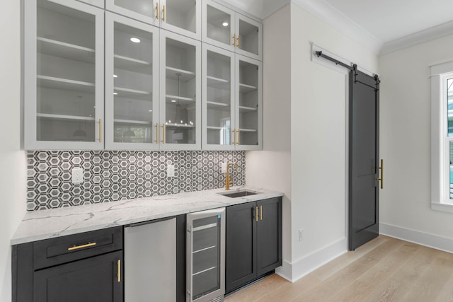 bar featuring light stone countertops, beverage cooler, a barn door, crown molding, and refrigerator